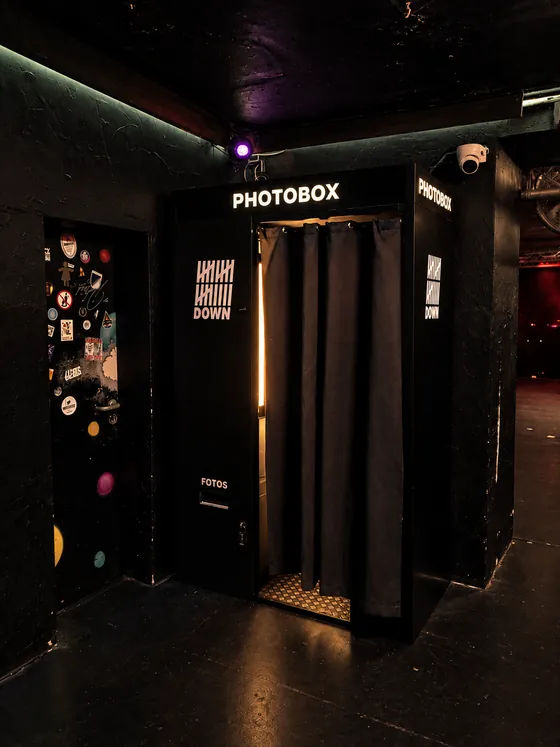 Schwarzer Fotoautomat mit weißem Photobox-Schriftzug und 19-Down-Logo in einem dunklen Club in Essen.