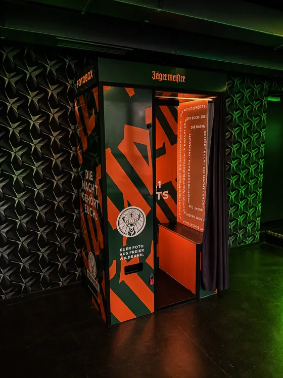 Grün-orange folierter Fotoautomat im Jägermeister-Design mit dem Spruch Die Nacht gehört euch, im Foyer der Columbiahalle Berlin.
